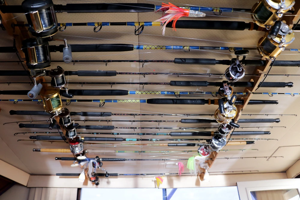 A display of various fishing rods and reels neatly arranged on a wooden rack, showcasing their colorful lines and accessories. A display of various fishing rods and reels neatly arranged on a wooden rack, showcasing their colorful lines and accessories.